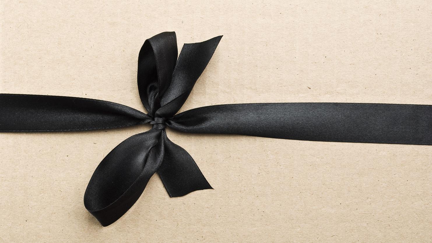 Schwarzes Satinband in Schleife auf braunem Geschenkpapier befestigt.