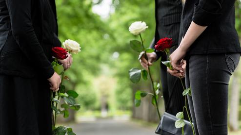 Vier Personen halten Rosen in einer parkähnlichen Umgebung, zwei rote und zwei weiße Blumen.